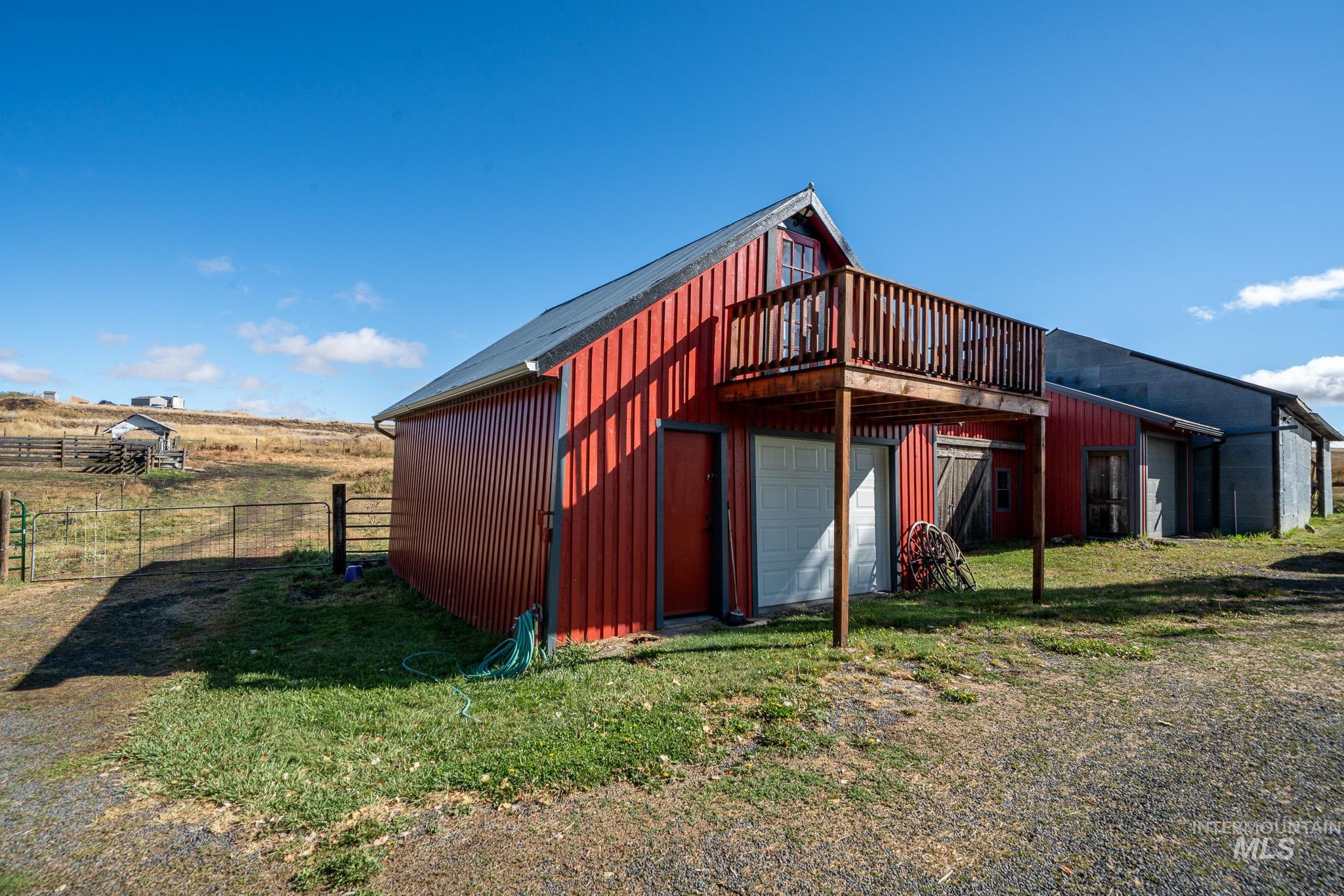 67 Jessup Road Grangeville, ID 83530 - Photo 21 of 49 Red corrugated metal siding structure featuring a wooden balcony, garage door, and metal roofing