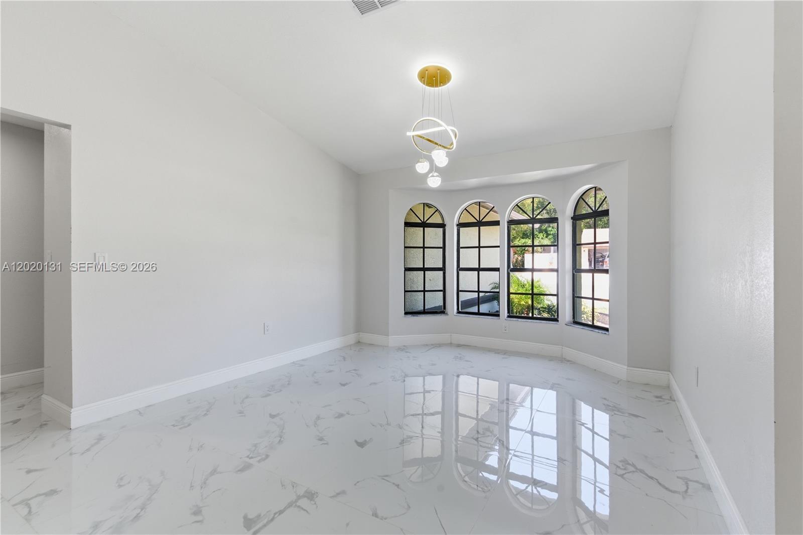 13408 Whitby Road Hudson, FL 34667 - Photo 12 of 30 an empty room with windows and chandelier