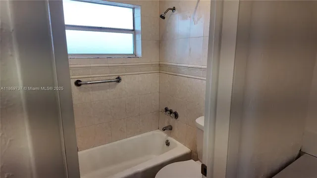 a bathroom with a bathtub toilet and window