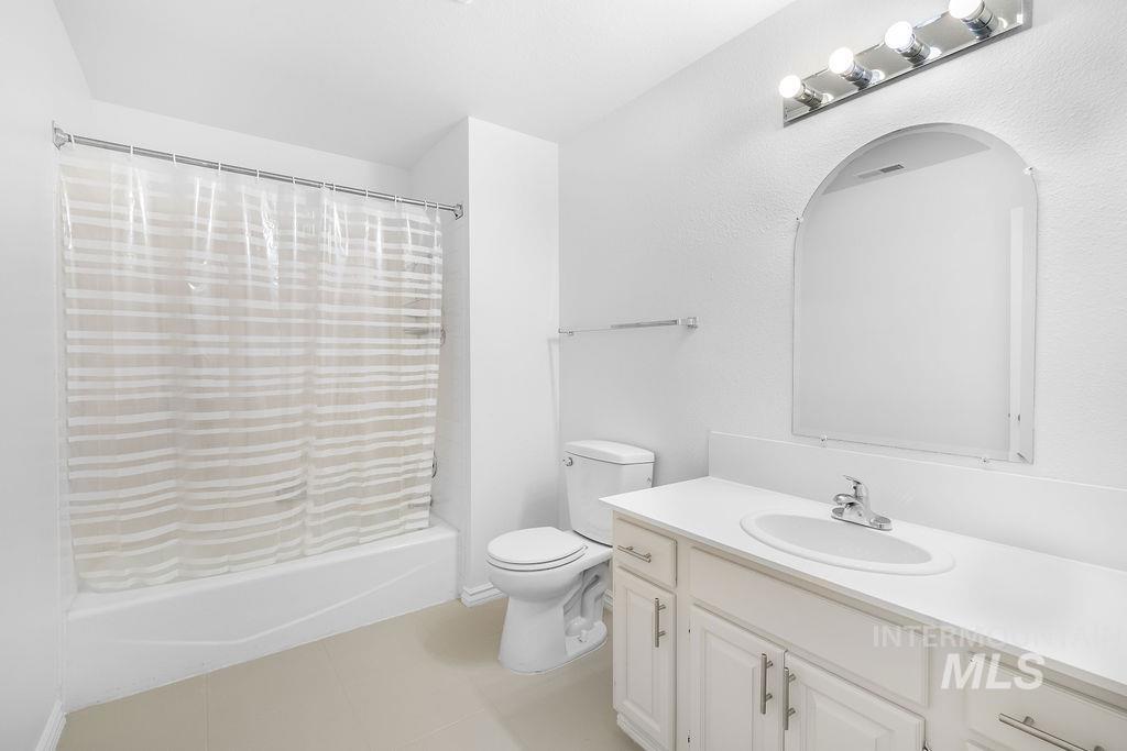 1561 Lenz Lane Boise, ID 83712 - Photo 14 of 29 Bathroom featuring vanity, shower / bathtub combination with curtain, and light tile patterned flooring