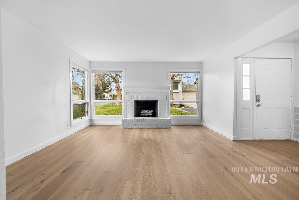 1561 Lenz Lane Boise, ID 83712 - Photo 4 of 29 Unfurnished living room with a brick fireplace and light wood-style flooring