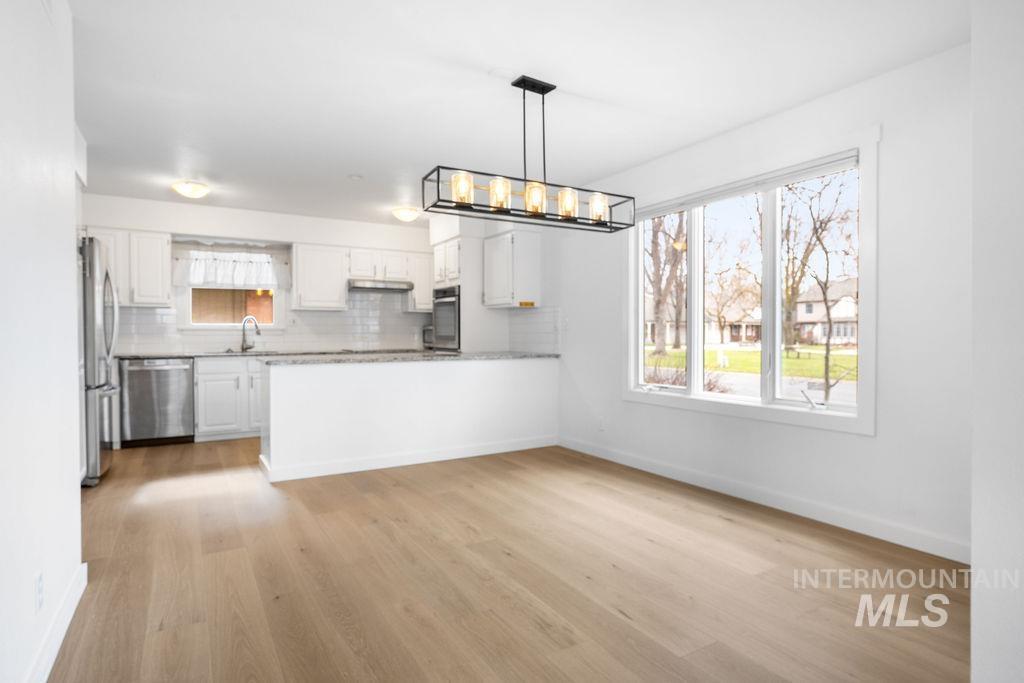 1561 Lenz Lane Boise, ID 83712 - Photo 6 of 29 Kitchen featuring white cabinetry, stainless steel appliances, healthy amount of natural light, and light wood-type flooring
