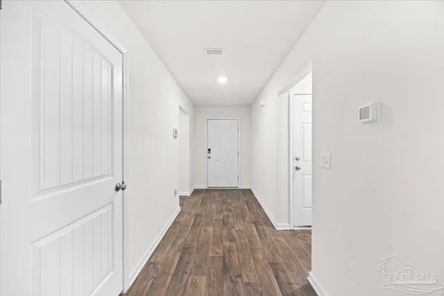 a view of a hallway with wooden floor and a bathroom