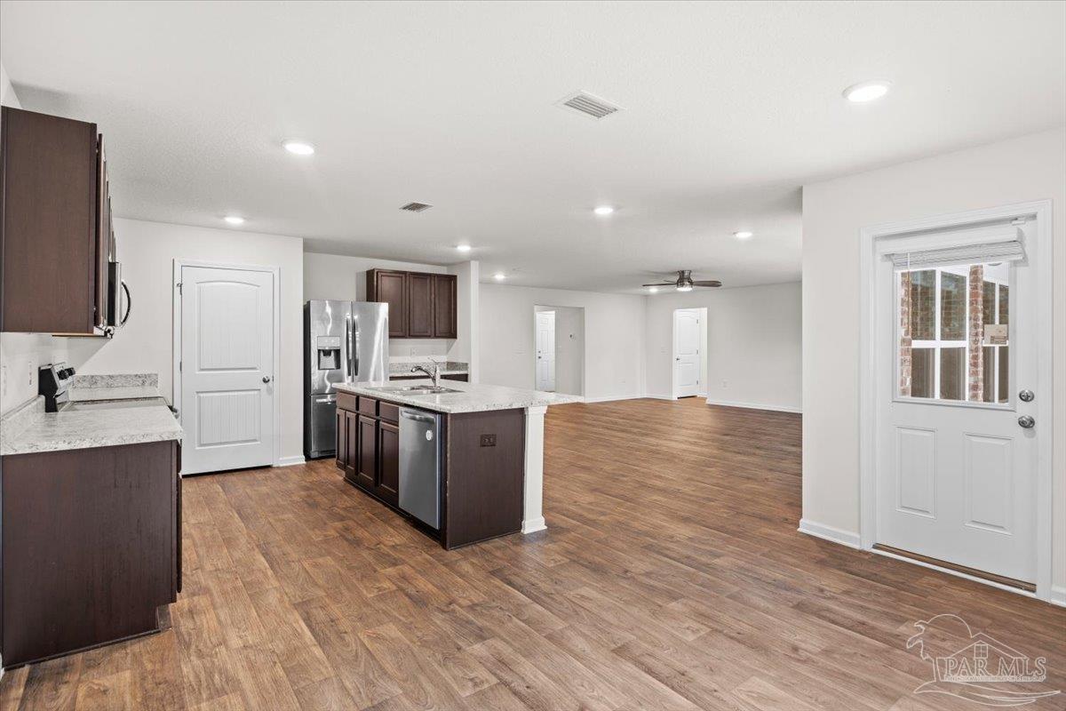 4666 Perception Circle Milton, FL 32570 - Photo 15 of 36 a large kitchen with kitchen island a sink dishwasher stove and white cabinets with wooden floor