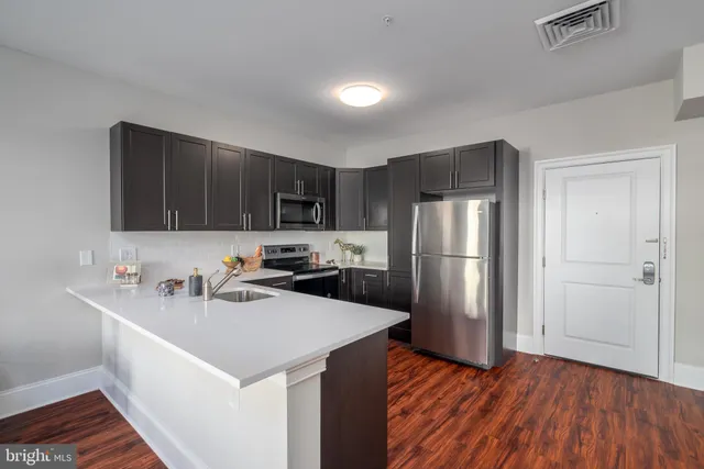 a kitchen with wooden cabinets a sink a stove a refrigerator and cabinets