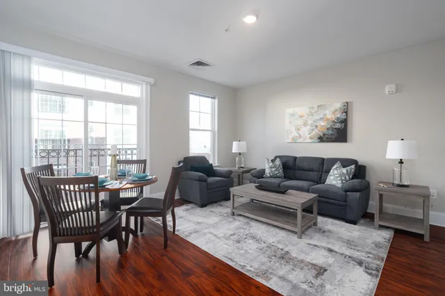 a living room with furniture wooden floor and a floor to ceiling window