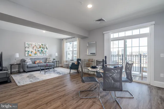 a living room with furniture large window and wooden floor