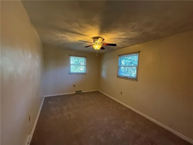 an empty room with windows and chandelier fan