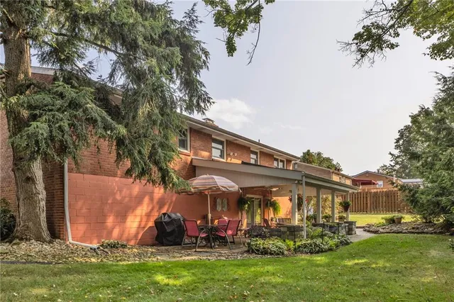 a view of a white house with a big yard and large trees