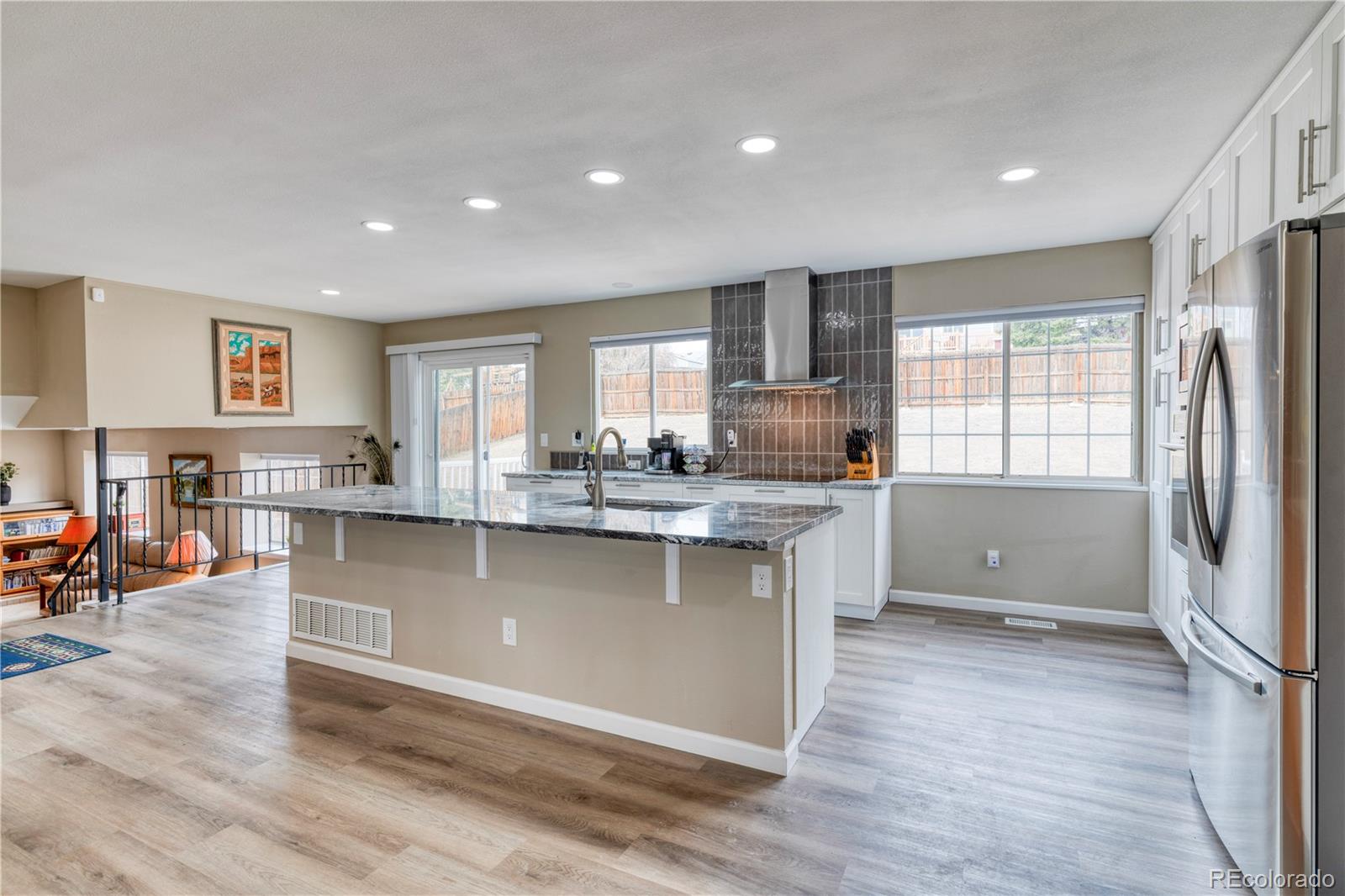6723 East Rustic Drive Parker, CO 80138 - Photo 7 of 32 a kitchen with stainless steel appliances granite countertop a refrigerator a sink a stove and white cabinets with wooden floor