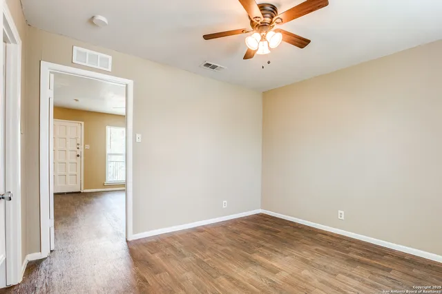 an empty room with a ceiling fan and wooden floor
