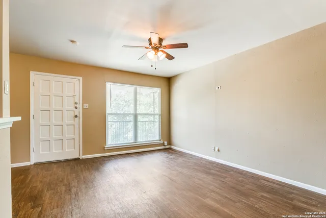 an empty room with windows and ceiling fan