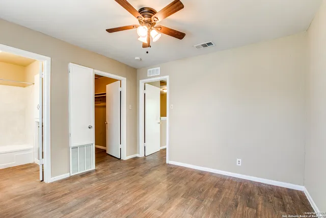an empty room with wooden floor chandelier fan and closet area