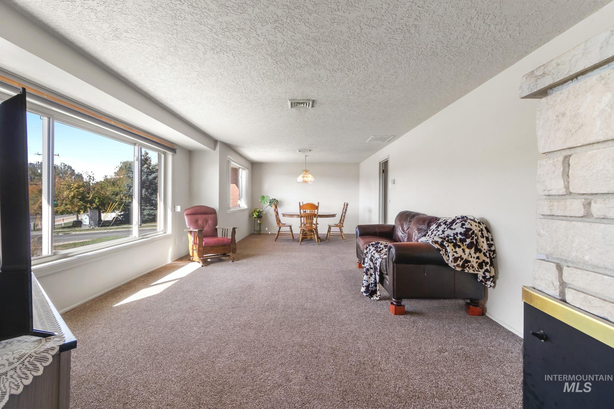 11360 West Lake Hazel Road Boise, ID 83709 - Photo 9 of 50 Expansive living area featuring a large picture window, neutral carpeting, and a built-in recessed ceiling light