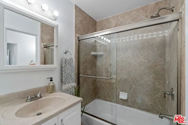 a bathroom with a shower sink and mirror