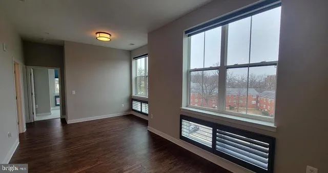 a view of an empty room with wooden floor and a window