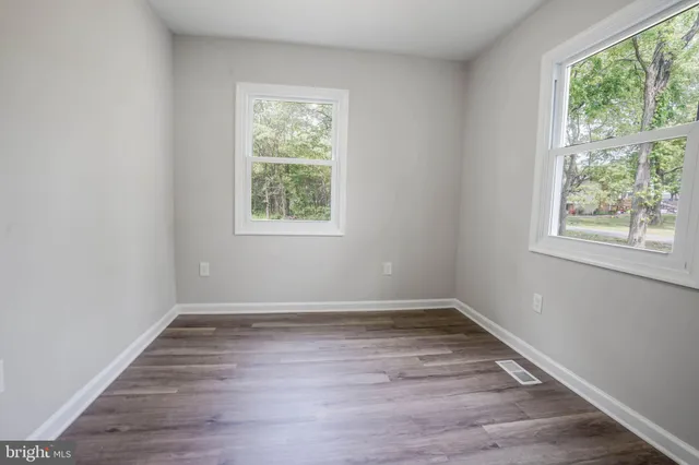 an empty room with wooden floor and window