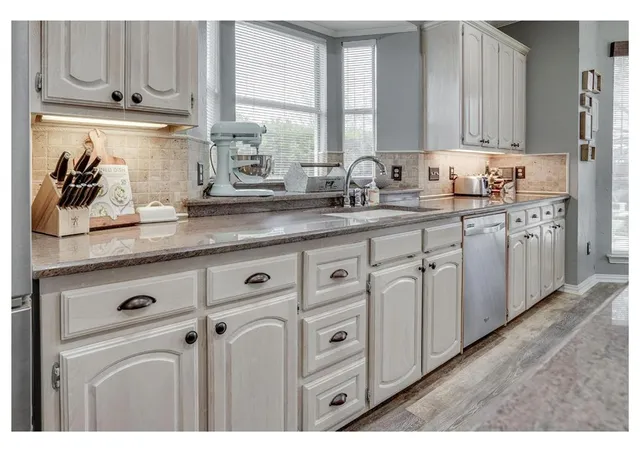 a kitchen with stainless steel appliances granite countertop white cabinets a sink and dishwasher with wooden floor