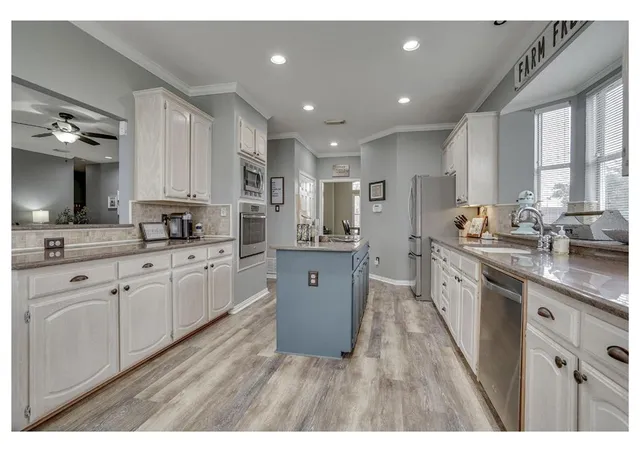 a kitchen with stainless steel appliances granite countertop a sink dishwasher stove and white cabinets with wooden floor