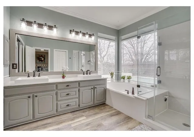 a spacious bathroom with a double vanity sink large mirror and a bathtub