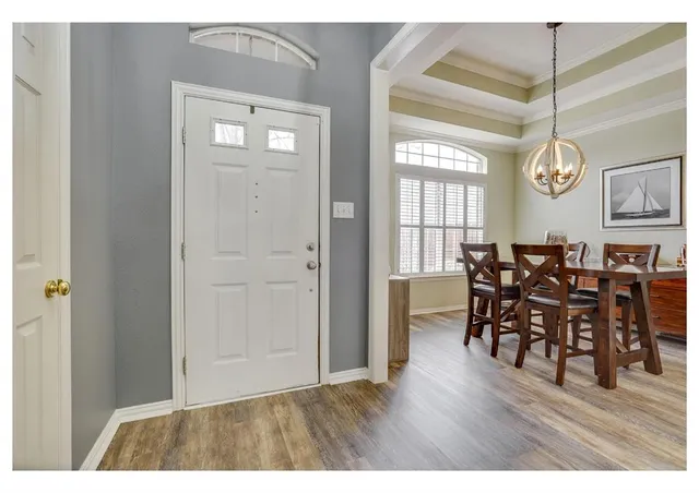 a view of a dining room and livingroom with furniture wooden floor a rug a painting and a chandelier