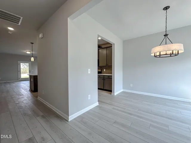 a view of a room with wooden floor kitchen and windows