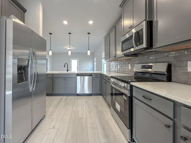 a large kitchen with stainless steel appliances kitchen island granite countertop a stove a sink and a microwave