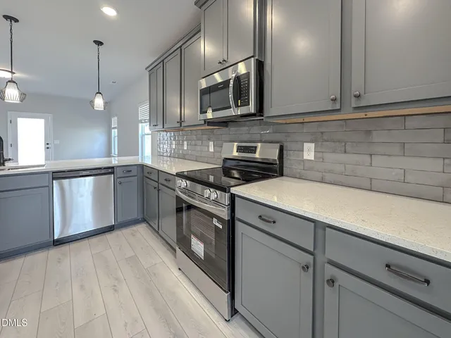 a kitchen with stainless steel appliances granite countertop a sink a stove and a microwave oven