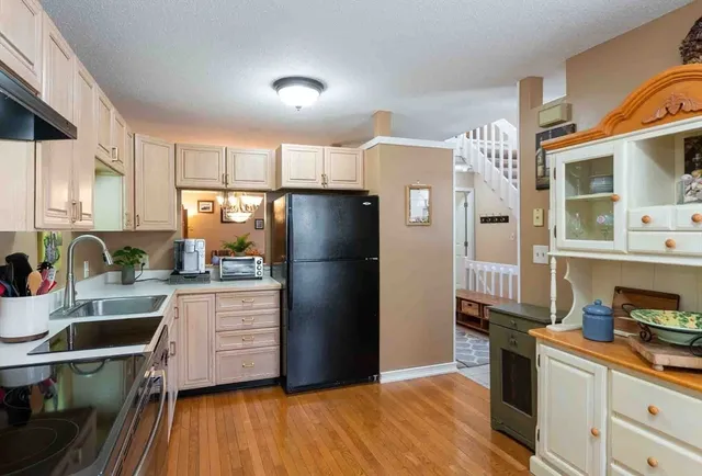 a kitchen with stainless steel appliances a refrigerator sink and wooden floor