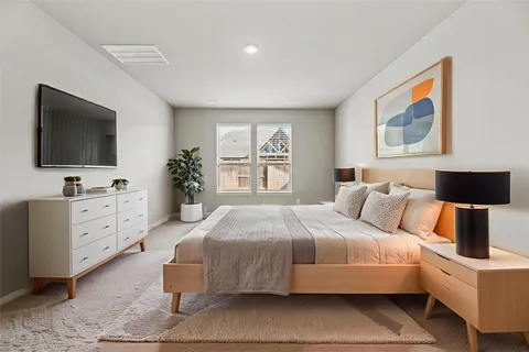 a bedroom with a large bed and a flat tv screen on dresser