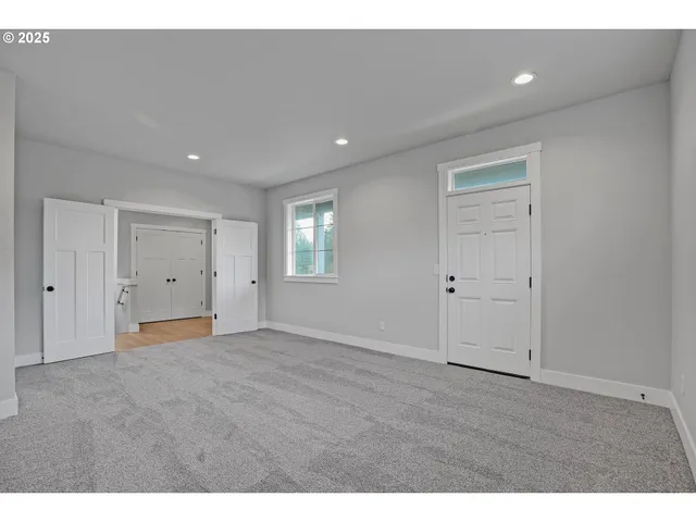 a view of an empty room with wooden floor and closet