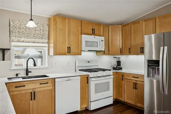 a kitchen with stainless steel appliances granite countertop a stove a sink a refrigerator and white cabinets with wooden floor