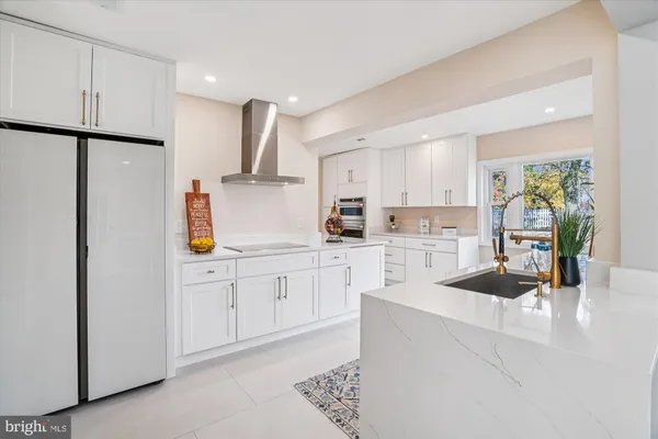 a kitchen with stainless steel appliances granite countertop a refrigerator sink and white cabinets