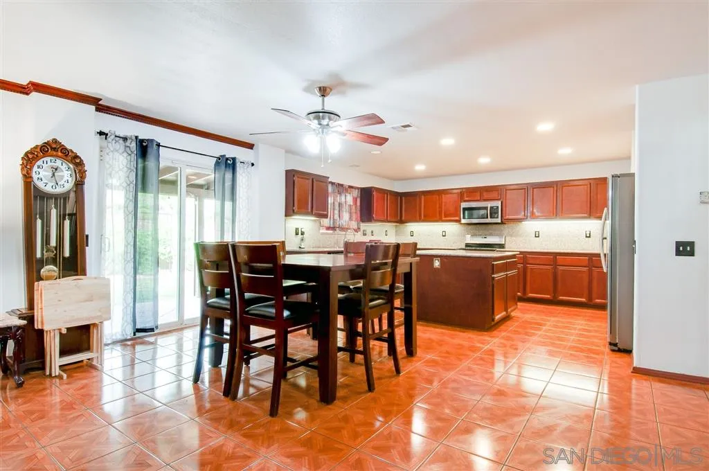 38305 Encanto Road Murrieta, CA 92563 - Photo 22 of 24 a open kitchen with stainless steel appliances kitchen island granite countertop a table chairs and a refrigerator