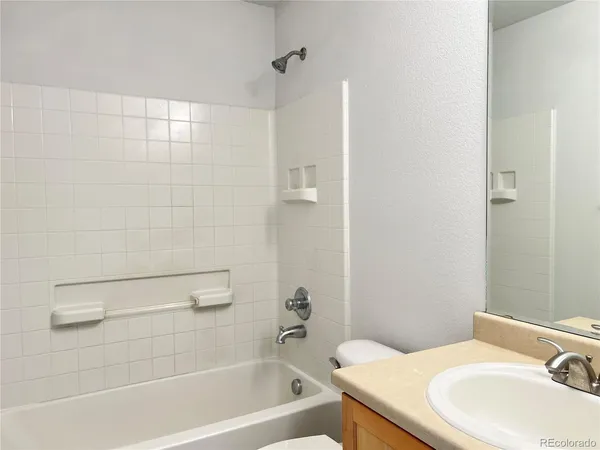 a bathroom with a granite countertop bathtub shower sink vanity and toilet