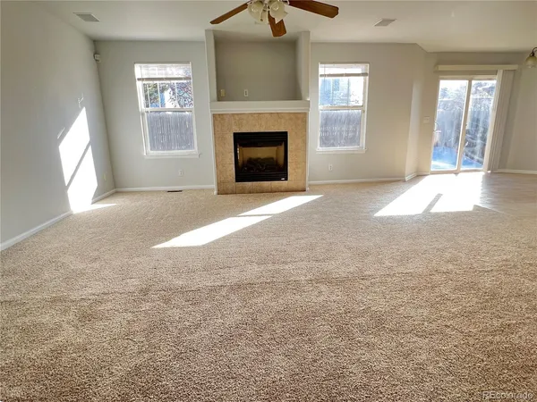 an empty room with windows and fireplace