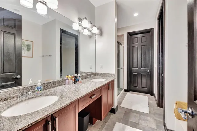 a spacious bathroom with a granite countertop double vanity sink a mirror and a shower