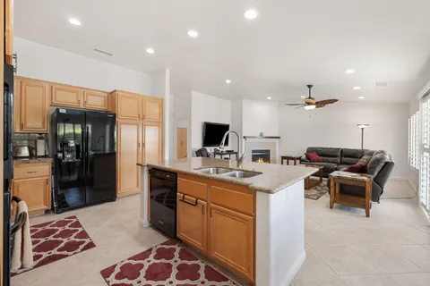 a large kitchen with stainless steel appliances kitchen island granite countertop a refrigerator and a sink
