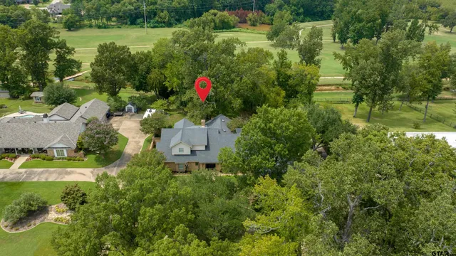 an aerial view of residential house with outdoor space and trees all around
