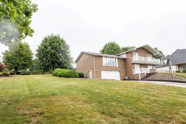 a view of a house with a big yard and large trees