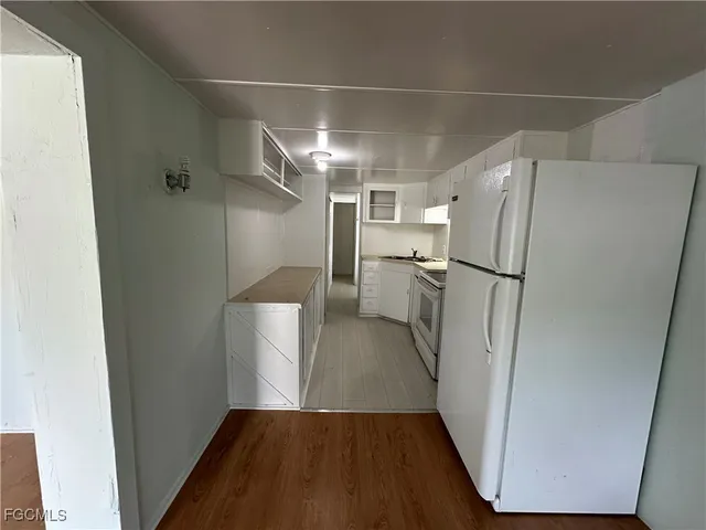 a view of a refrigerator in kitchen and an empty room