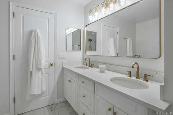 a bathroom with a double vanity sink toilet and shower