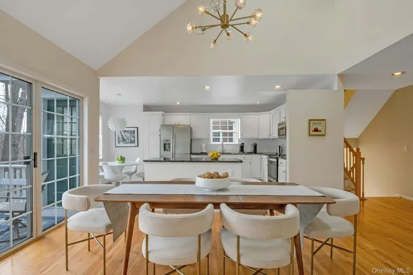 a kitchen with stainless steel appliances kitchen island granite countertop a stove a refrigerator a sink a dining table and chairs with wooden floor