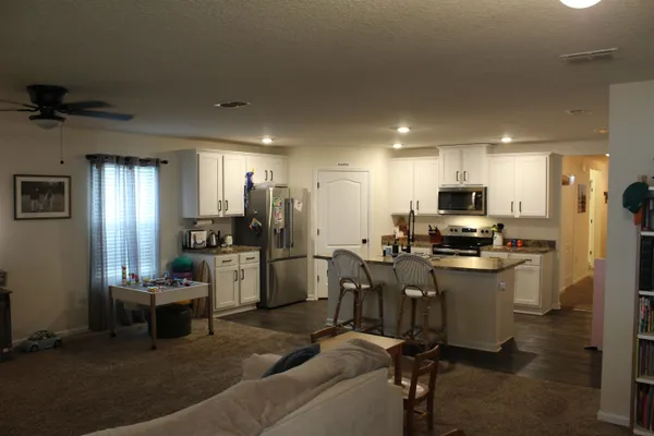a kitchen with granite countertop a refrigerator and a stove top oven