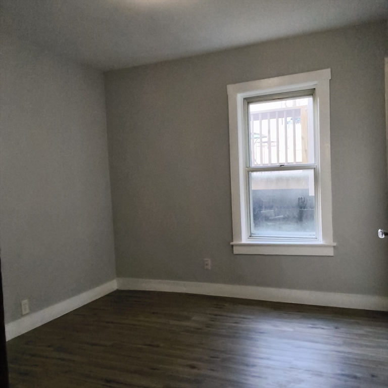 212-218 Lowell Street, Unit 1E Fall River, MA 02721 - Photo 5 of 10 a view of an empty room with wooden floor and a window