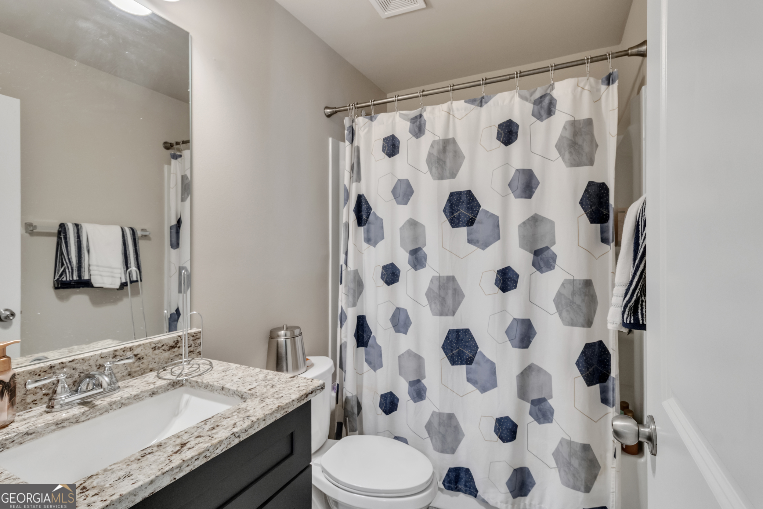 11614 Alcovy Road Covington, GA 30014 - Photo 49 of 62 a bathroom with a granite countertop toilet a sink and a mirror
