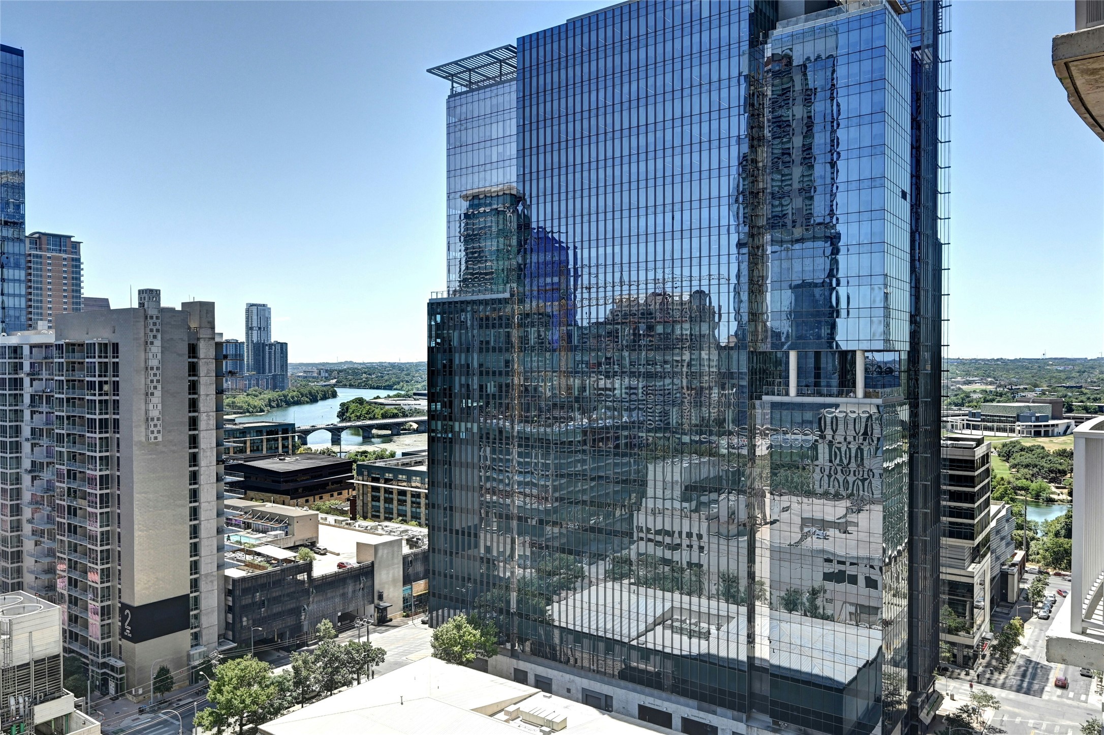 360 Nueces Street, Unit 1809 Austin, TX 78701 - Photo 23 of 25 Modern high-rise featuring a reflective glass facade, multiple stories, and a prominent rooftop architectural element