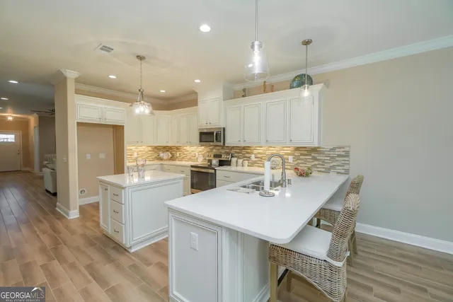 a kitchen with a sink a center island stainless steel appliances and cabinets