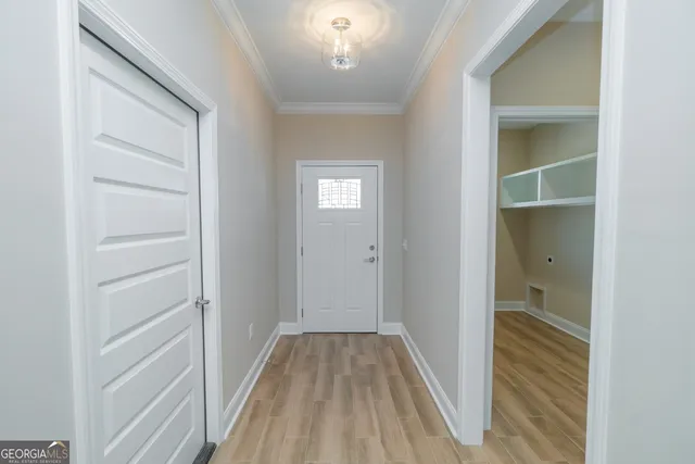 a view of a hallway with wooden floor and a bathroom
