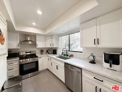 a kitchen with a sink white cabinets and appliances